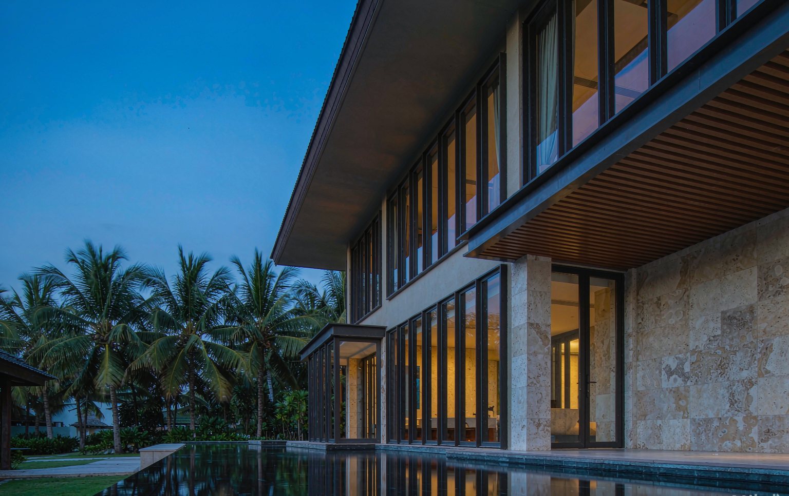 Tropical villa at dusk with floor-to-ceiling aluminum windows
